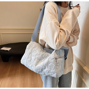 Detail of light blue quilted shoulder bag with 3D floral stitching on durable fabric
