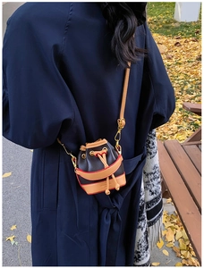 Mini sac seau à cordon en cuir grainé porté avec un trench-coat aux couleurs d'automne