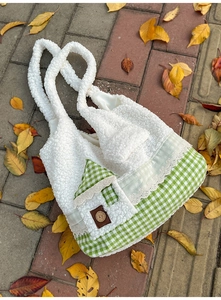 Détail du sac en peluche blanc avec base à carreaux verts et poche créative en maison