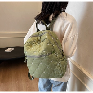 Detail of green quilted backpack with white bow embroidery and secure double zipper closure