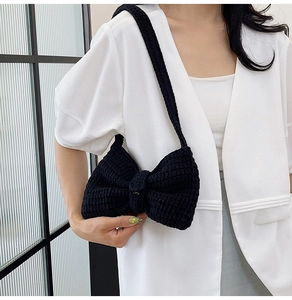Détail d'un sac à bandoulière fait main en tricot noir avec un nœud et texture crochet