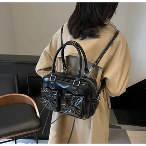 Detail of black glossy backpack with bow pockets on a model wearing a beige trench coat