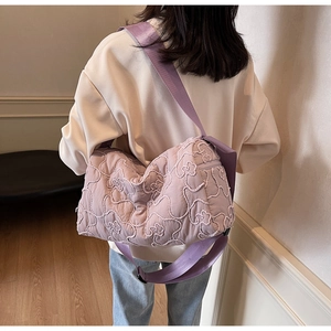 Rear view of a model wearing a lavender quilted crossbody bag with bear embroidery