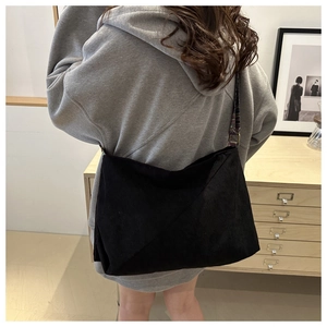 Détail du sac cabas en velours côtelé noir avec bandoulière rayée porté par un mannequin
