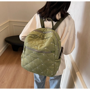 Detail of olive green quilted backpack with white bow embroidery and diamond stitching