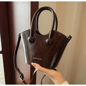 Close-up of a chocolate brown bucket bag with shiny leather texture and gold sphere details