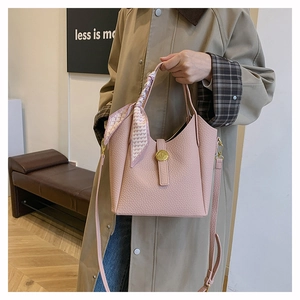 Pink bucket bag with lychee texture featuring a gold twist lock and a silk scarf handle