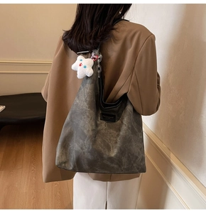 Detail of grey washed leather tote bag with fashion label and white star plush pendant
