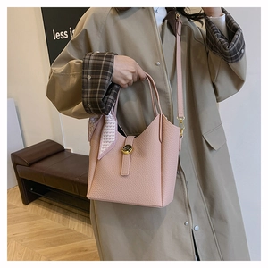 Pink lychee grain leather bucket bag with silk heart scarf shown on a trench coat
