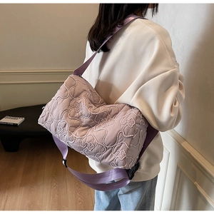 Detail of purple quilted shoulder bag with white bear embroidery and adjustable strap