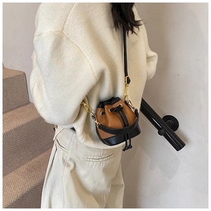 Détail du mini sac seau en cuir marron avec cordon de serrage et bordures noires