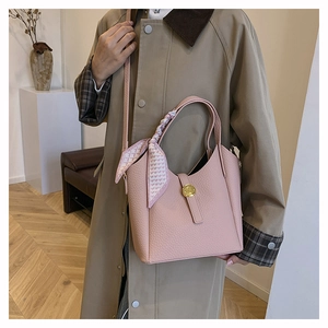 Detail of pink lychee leather bucket bag with gold clasp and heart print silk scarf