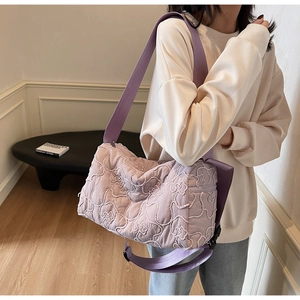 Detail view of the purple quilted crossbody bag showing the floral pattern and wide strap