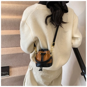 Détail d'un mini sac seau en cuir marron et noir avec des finitions en métal doré