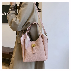 Detailed close-up of pink litchi leather bucket bag with silk scarf and gold buckle