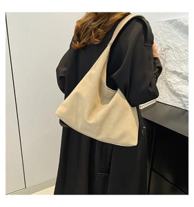 Vista dettagliata della borsa hobo beige minimalista indossata su un cappotto nero