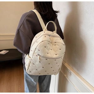 Quilted white backpack with bow embroidery shown on model for size perspective