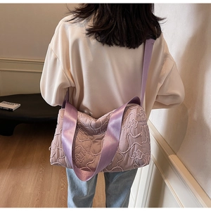Close-up of a purple quilted nylon shoulder bag with floral texture on a female model