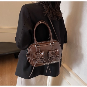Detail view of vintage caramel brown leather bag with symmetrical bow pockets and top handle