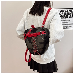 Detail of heart-shaped black itabag featuring a transparent window and red bow accents