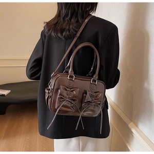 Detail of dark brown vintage gloss leather bag with decorative bow pockets and silver hardware