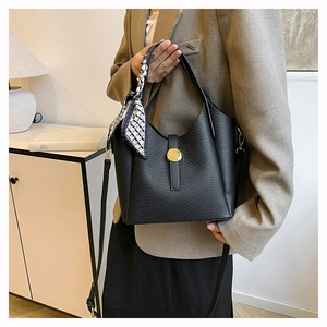 Detail of black lychee grain leather bucket bag with gold hardware and silk scarf decor