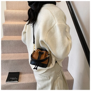 Détail du mini sac seau bicolore avec fermeture à cordon et crochets dorés chics