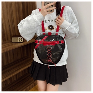 Detailed view of a heart-shaped black leather backpack with red ribbons and metal hardware