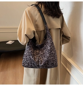 Detalle de bolso hobo con estampado de leopardo y correa de cuero sobre una gabardina beige