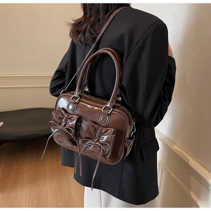 Vintage brown leather handbag with bow pockets shown on model with black suit blazer
