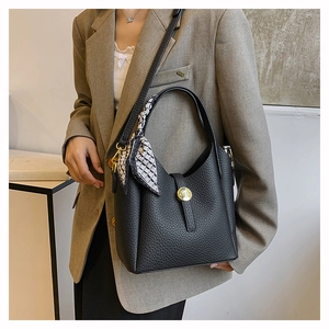 Detail of black pebbled leather bucket bag with gold buckle and checkered silk scarf