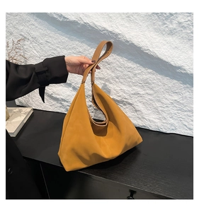 Dettaglio della borsa tote in pelle senape con cuciture laterali e pieghe morbide