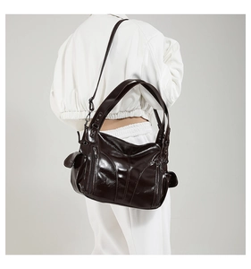 Detailed view of dark brown glossy PU leather tote bag with functional exterior zippers