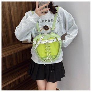 Detail view of a light green apple-shaped ita bag featuring a heart-shaped clear window