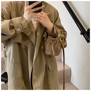 Détail d'un mini sac seau marron à cordon avec ferrures dorées et cuir grainé litchi