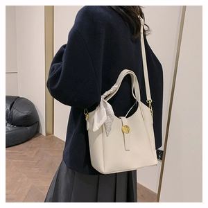 Close-up of white bucket bag featuring lychee grain texture and elegant printed silk scarf