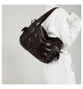 Detailed side view of high-gloss dark brown tote bag with multi-zipper compartments