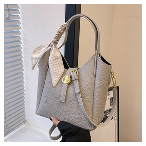 Detail of grey lychee leather bucket bag with decorative heart pattern silk scarf and gold buckle