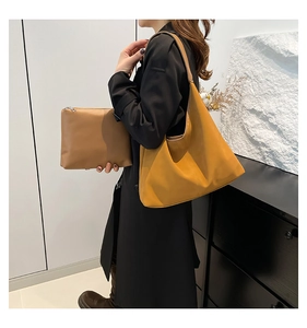 Dettaglio della borsa tote in pelle giallo senape abbinata a un trench nero lungo