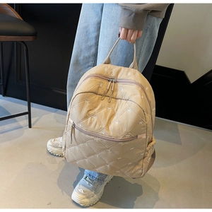 Detail of the quilted rhombic pattern and bow print on this khaki school backpack