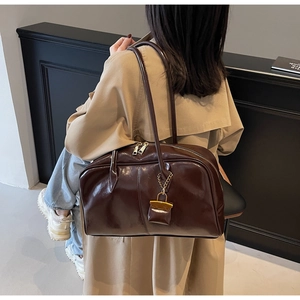 Detail of dark brown high-gloss PU leather shoulder bag with gold lock and mini pouch