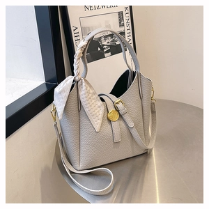 Detail of grey lychee leather bucket bag with silk scarf handle and gold relief buckle