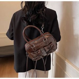 Detailed back view of a dark brown bow-knot handbag with glossy leather and fringe detail