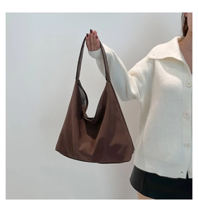 Vista dettagliata di una grande borsa hobo marrone portata da una modella in abiti casual
