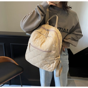 Detailed close-up of beige quilted backpack with bow embroidery and drawstring side pocket