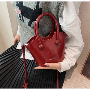 Detail of red patent leather bucket bag with top handle and Rioa & Luxury logo text