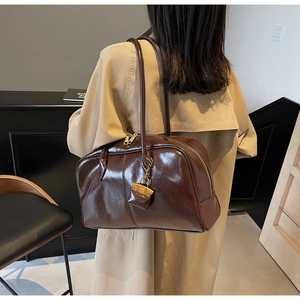 Detailed view of brown oil-wax PU leather shoulder bag with a small hanging decorative pouch