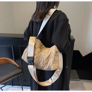 Detail of floral quilted texture and large black buckle on khaki crossbody bag