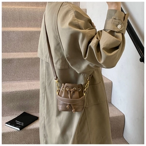 Détail d'un mini sac seau marron à cordon porté en bandoulière par une petite fille