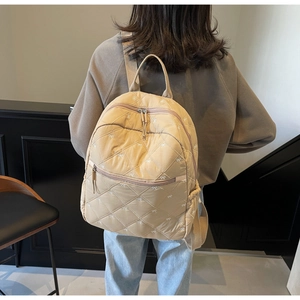 Detailed back view of a beige quilted backpack featuring a cute bow pattern and side pockets